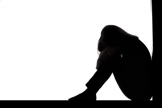 silhouette of a woman sitting on the floor in a corner on a white ...